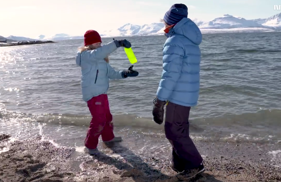 To barn som fjerner en plastflaske fra havet