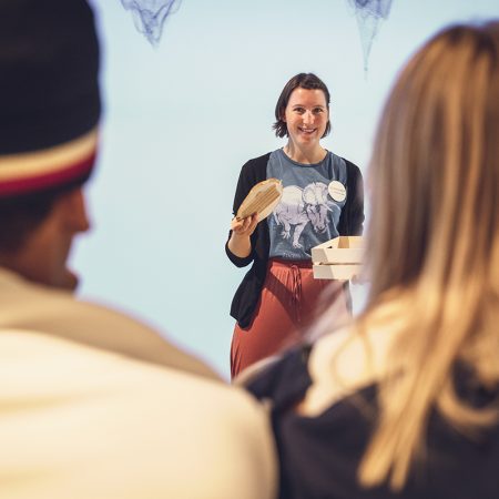 dame i en undervisningssituasjon med to elever med ryggen til