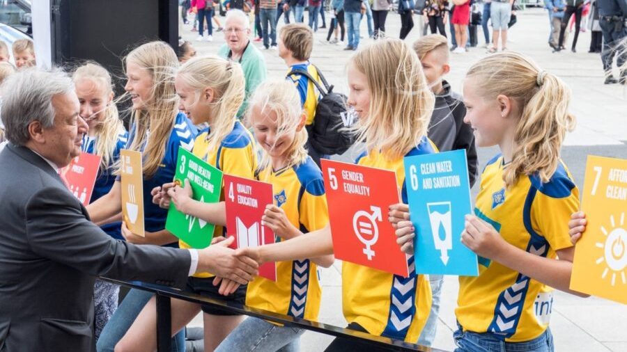 Guterres møter barn med plakater med bærekraftsmålene